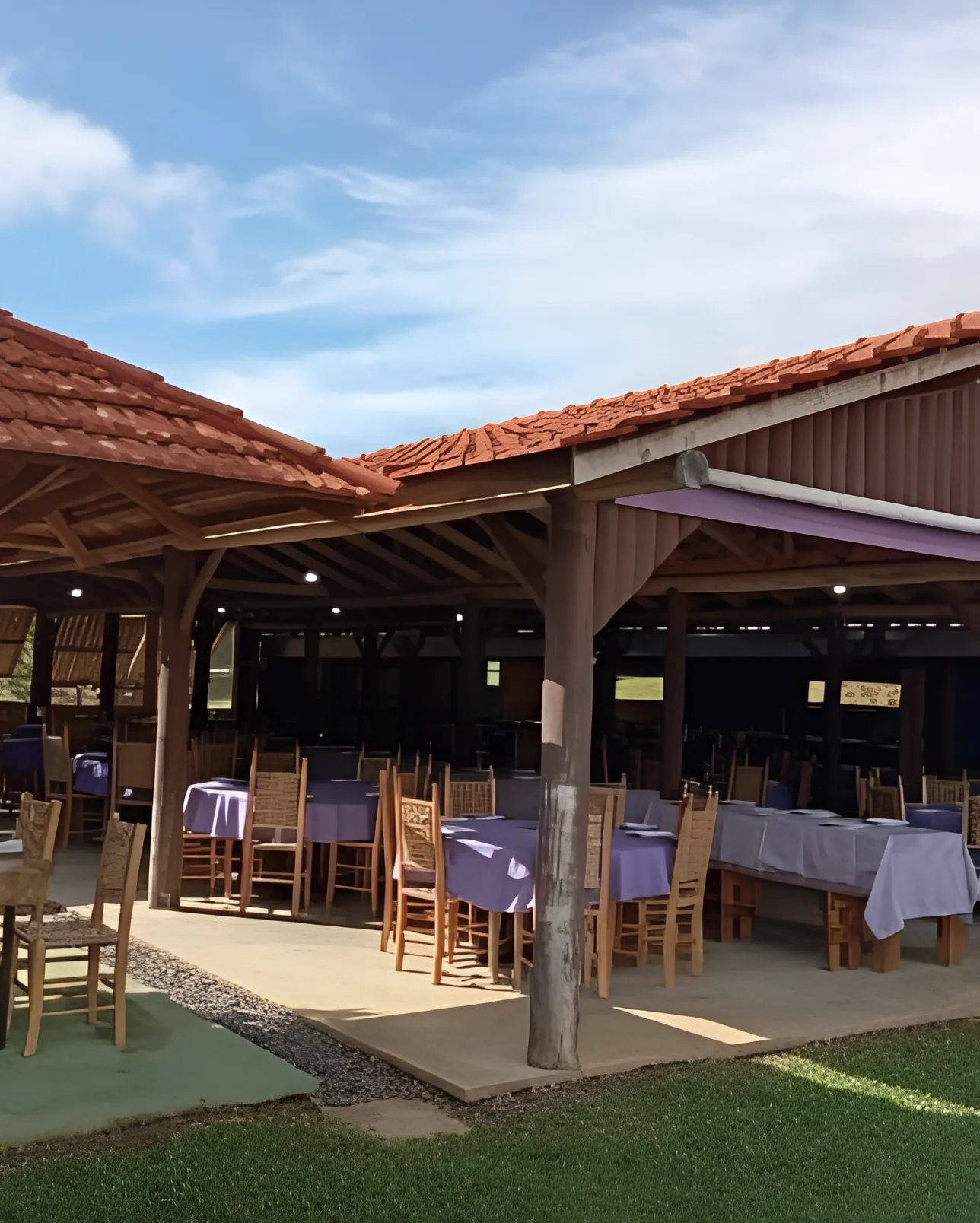 Restaurante com mesas montadas e gramado ao redor